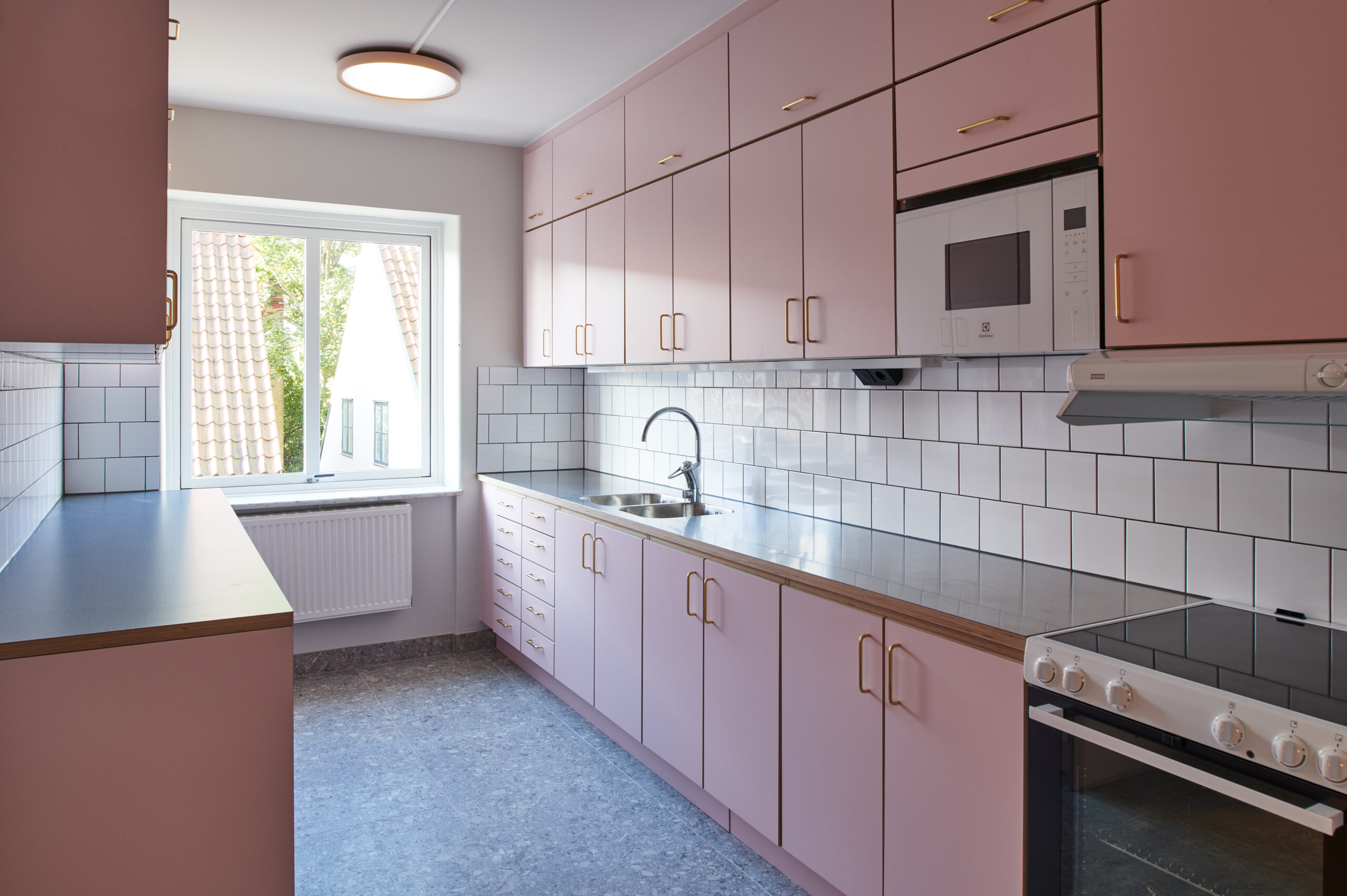 Ett rosa kök med vitt kakel