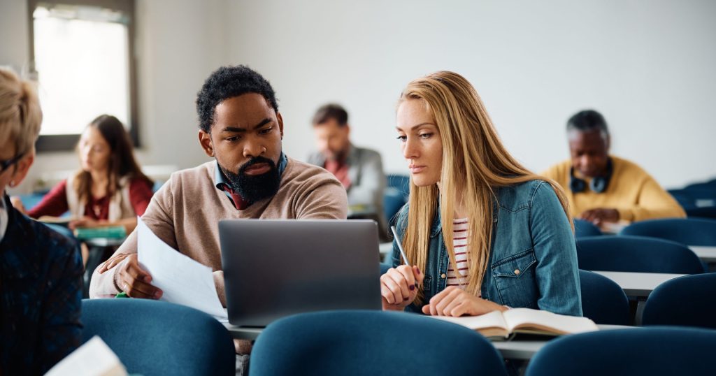 students cooperating while e-learning on laptop during education training course in the classroom.