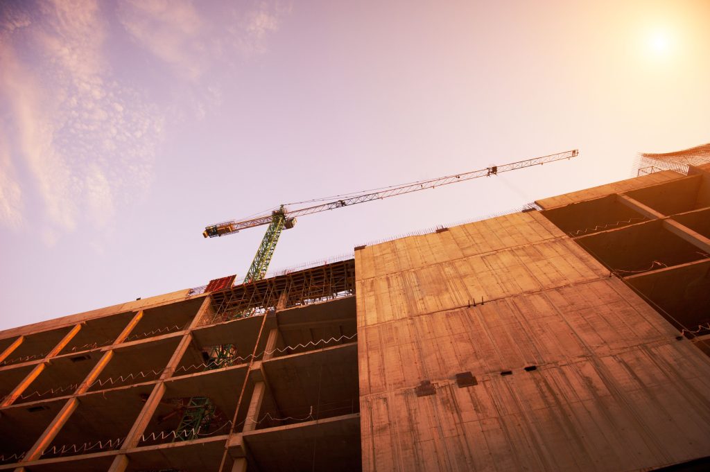 construction of a building by cranes in the afternoon